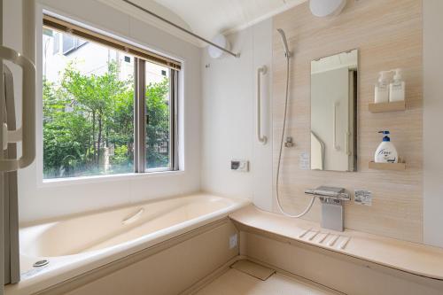 a bathroom with a tub and a sink and a window at SHINJUKU Garden-house in Tokyo