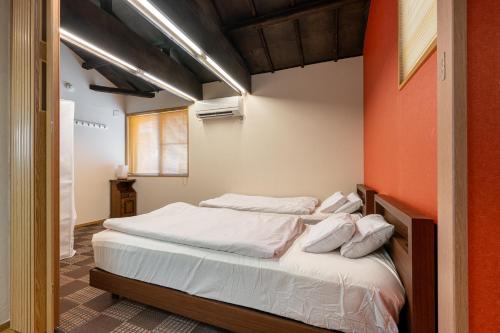 a bedroom with two beds and an orange wall at SHINJUKU Garden-house in Tokyo