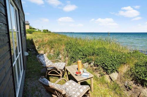 a table and chairs sitting next to the ocean at 20414-Samso-Strandvejen-63 in Ballen