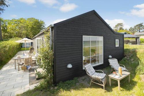 a black house with two chairs and a table at 20414-Samso-Strandvejen-63 in Ballen