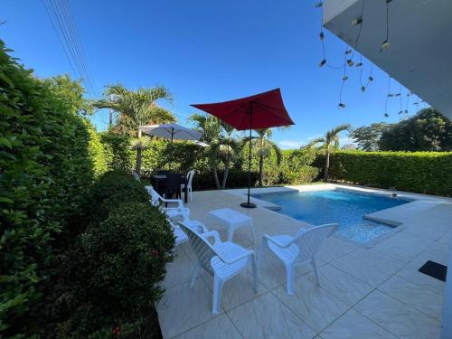 a patio with chairs and an umbrella and a pool at Sunset Private Villa in Ricaurte in Llano del Pozo