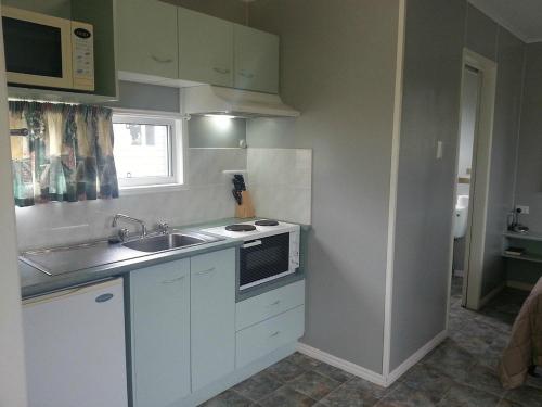 a small kitchen with a sink and a stove at Bushchooks Travellers Village in Bororen