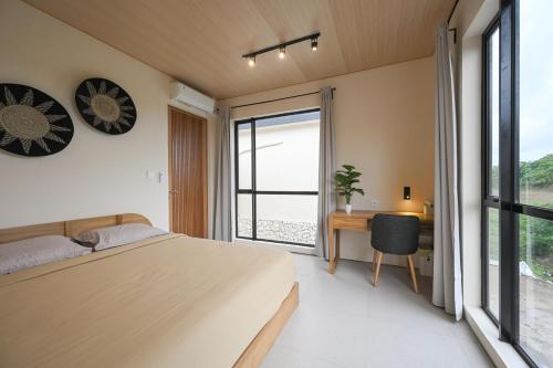a bedroom with a bed and a desk and a window at Kedungu Village by Hello Summer in Tabanan