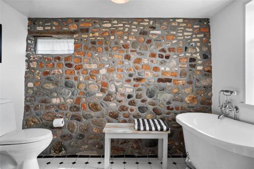 a bathroom with a stone wall next to a toilet and a tub at 20304-Samso-Orby-Hovedgade-35 in Brundbymark