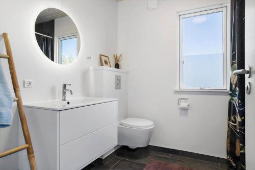 een witte badkamer met een toilet en een spiegel bij 20142-Samso-Laerkevej-9-C in Nordby