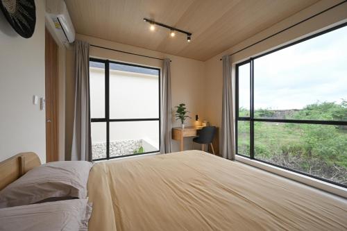 a bedroom with a bed and a large window at Kedungu Village by Hello Summer in Tabanan