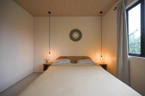 a bedroom with a large bed and a clock on the wall at Kedungu Village by Hello Summer in Tabanan