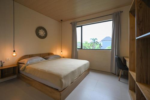 a bedroom with a bed and a large window at Kedungu Village by Hello Summer in Tabanan