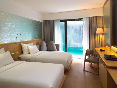 a hotel room with two beds and a desk at IZE Seminyak by LifestyleRetreats in Seminyak