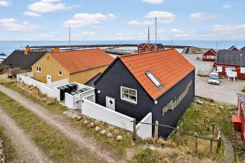 a black house with an orange roof next to the ocean at 20123-Samso-Maarup-Havn-7-A in Nordby