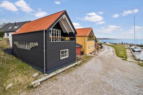 a black house with an orange roof on a gravel road at 20123-Samso-Maarup-Havn-7-A in Nordby