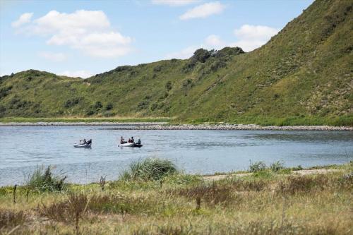 three people in boats on a river with a mountain at 20123-Samso-Maarup-Havn-7-A in Nordby