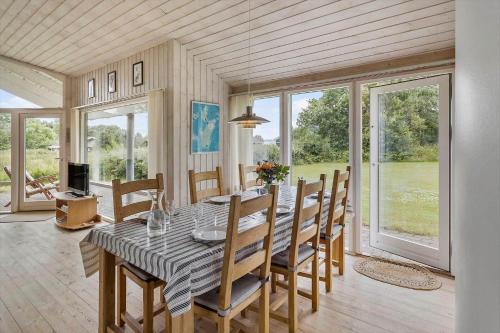 a dining room with a table and chairs and windows at 20109-Samso-Rosenvej-88 in Tanderup