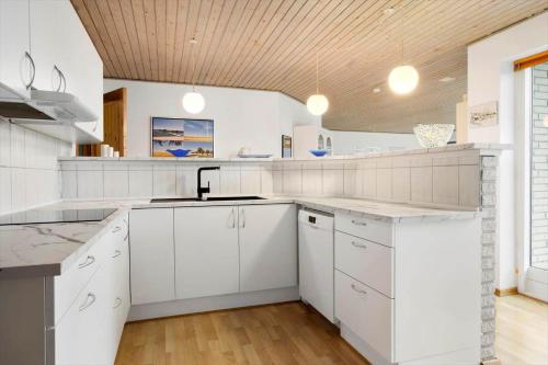 a kitchen with white cabinets and a wooden ceiling at 20416-Samso-Strandvejen-10-A in Ballen