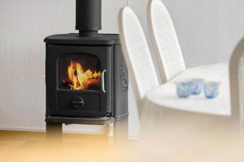 a black stove with a fire in it next to a chair at 20416-Samso-Strandvejen-10-A in Ballen