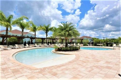 a pool at a resort with palm trees and chairs at Great and practical townhouse in gated community, sleeps 6 10 min to Disney! in Orlando