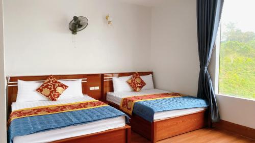 two beds in a room with a window at Cô Tô Lương Chi in Quang Ninh