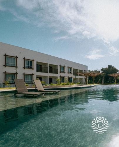 a swimming pool with two chairs in front of a building at Pipa Privilege Ocean in Pipa