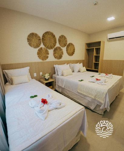 two beds in a hotel room with flowers on them at Pipa Privilege Ocean in Pipa