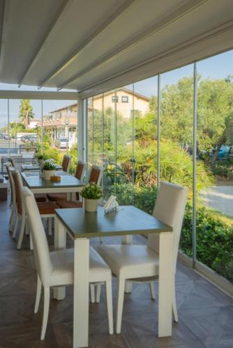 Un comedor con mesas y sillas y ventanas. en Isa Residence Fiumicino Airport, en Fiumicino