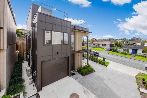 a house with a brown door on a street at Holiday Escape Modern 4BR Home by Waiake Beach in Auckland