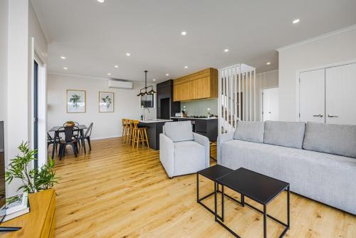 a living room with a couch and a table at Holiday Escape Modern 4BR Home by Waiake Beach in Auckland