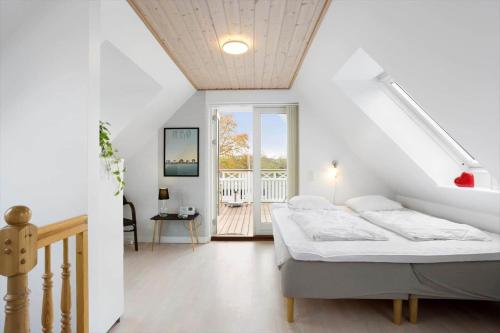a white bedroom with a bed and a balcony at AE285-Aeroskobing-Hanses-Ager-4 in Ærøskøbing
