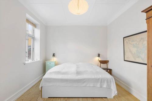 a white bedroom with a bed and a window at AE208-Aeroskobing-Brogade-4 in Ærøskøbing