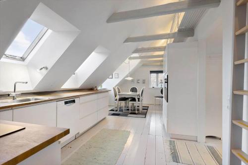 an attic kitchen with white cabinets and a table at AE284-Aeroskobing-Gyden-13 in Ærøskøbing
