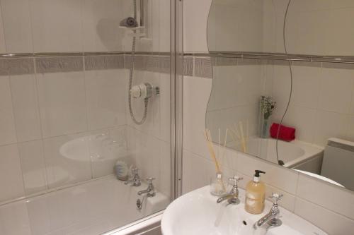 a white bathroom with a sink and a shower at Pintail Apartment Bamburgh in Bamburgh