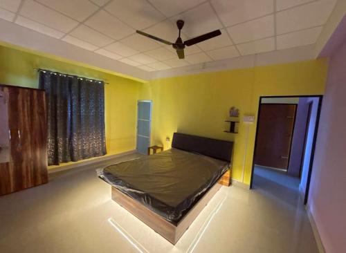 a bedroom with a bed in a room with yellow walls at Niroda Guest House, Jorhat in Jorhat