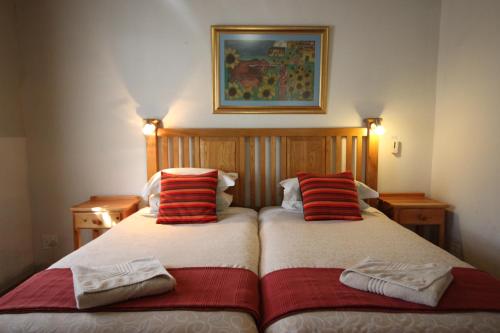 a bedroom with two beds with red and white pillows at Donkin Country House in Beaufort West