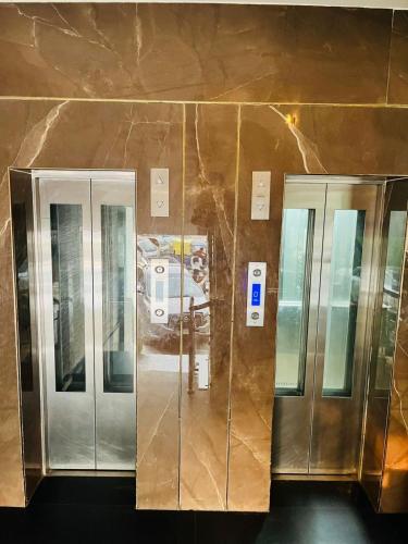 three elevators in a building with a marble wall at Trimrooms Triumph Banaras Railway Station in Varanasi