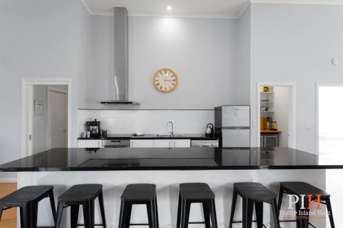 a kitchen with black stools and a counter with a clock at Family Home Silverleaves Sleeps 12 in Rhyll