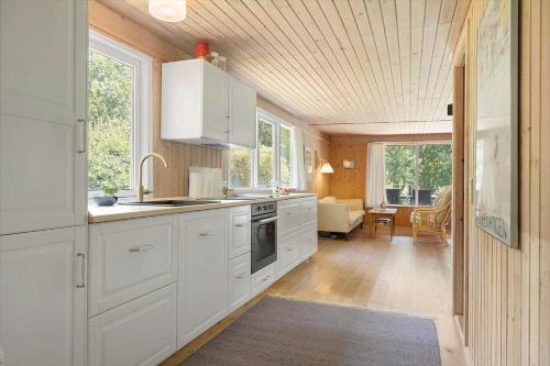a kitchen with white cabinets and a living room at TV1586-Jerup-Kuskevej-5 in Jerup