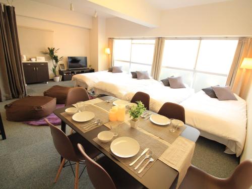 a hotel room with two beds and a table and chairs at アーバンポイント富士見 Urban Point Fujimi in Nagoya
