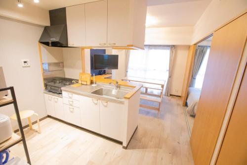 a kitchen with white cabinets and a sink at SN3A 大須徒歩10分 TV,パソコンなど設備充実 木の温もりあるナチュラルな部屋 8人可 10-minute walk to Osu Fully equipped with TV, PC, etc Natural wooden warm rooms Accommodates 8 people in Nagoya
