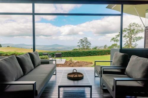 a living room with a couch and a large window at Maleny Scenic Retreat in Booroobin