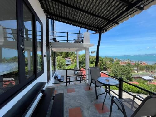 a balcony of a house with a table and chairs at Joy Houses Haadrin in Haad Rin