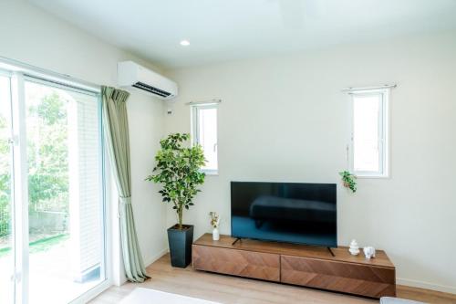 a living room with a large flat screen tv at Villa NIRAI in Uruma