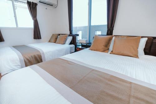 a hotel room with two beds and a window at Villa NIRAI in Uruma