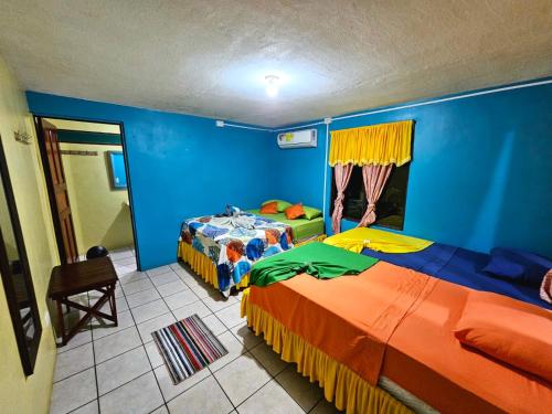 two beds in a room with blue walls at Cabinas Miss Miriam 2 in Tortuguero