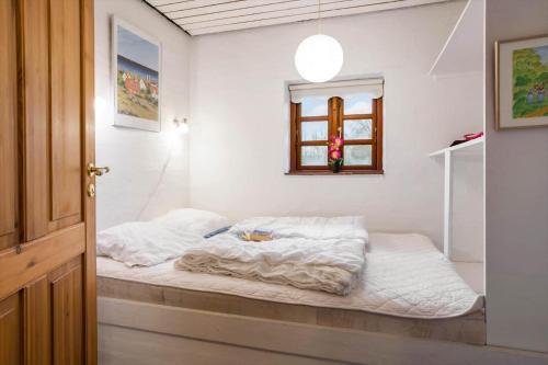 a bedroom with a bed with white sheets and a window at 20145-Samso-Skovvejen-14 in Nordby