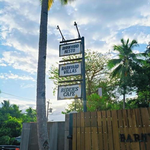 a group of signs on a pole next to a palm tree at El Grande Barn Yard in Davao City