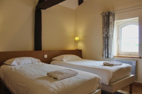 two beds in a hotel room with a window at La Bullote - Gîtes - Paris Roissy CDG in Villeneuve-sous-Dammartin