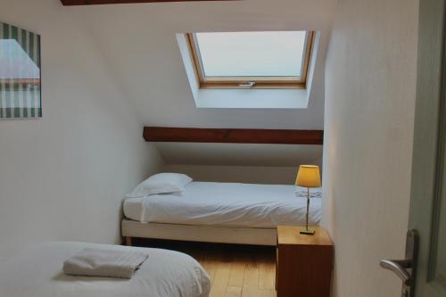 a small room with two beds and a window at La Bullote - Gîtes - Paris Roissy CDG in Villeneuve-sous-Dammartin