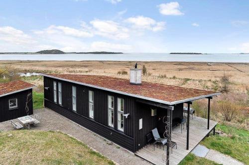 a black house with a roof on the beach at 20420-Samso-Alstrup-15-C in Toftebjerg