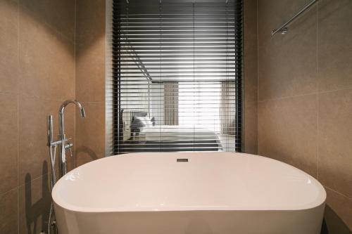 a white tub in a bathroom with a window at Dom's Residence Hoan Kiem in Hanoi