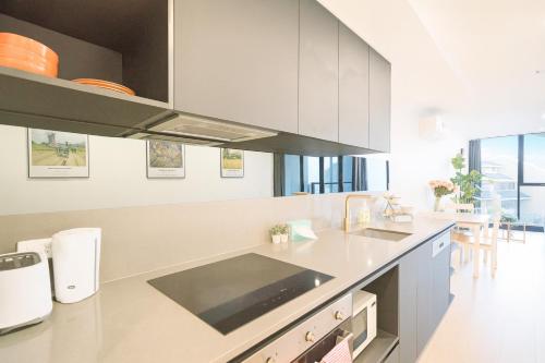 a kitchen with white cabinets and a counter top at Easeful Canberra CBD 2BR Apt in Canberra