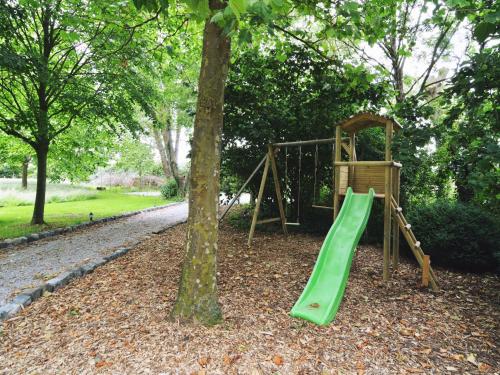 a playground with a green slide next to a tree at Holiday Home in Alveringem near Coast in Leisele